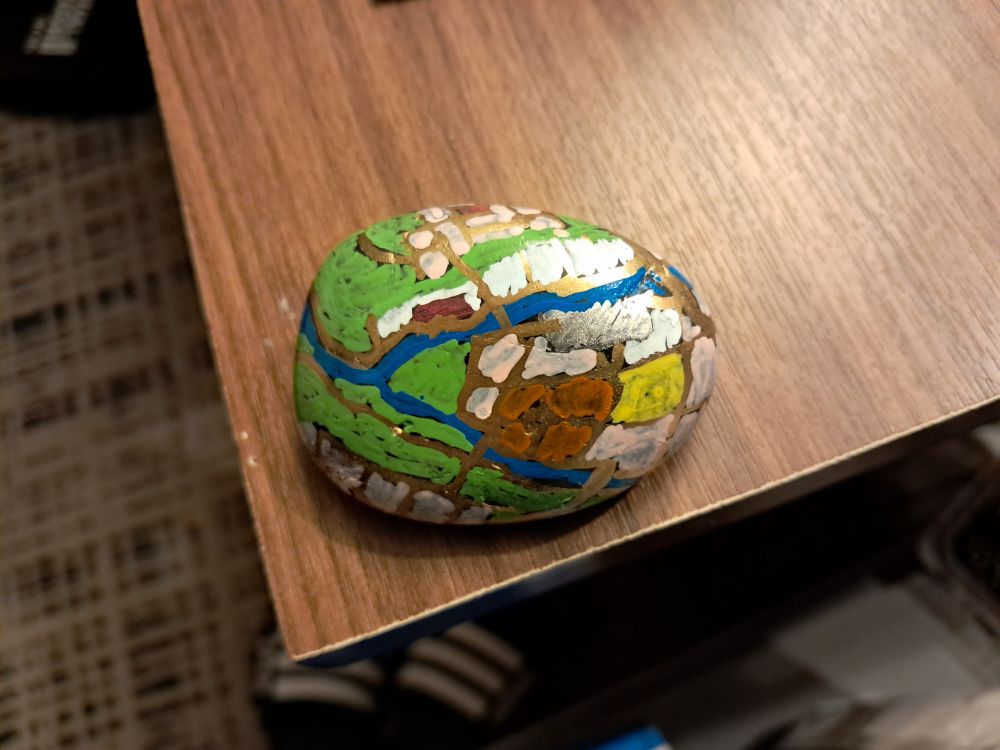 A painted rock, with a simplified yet colorful map of Pittsburgh