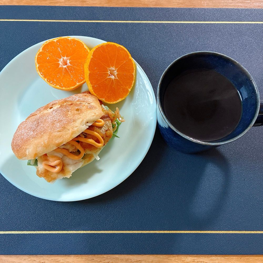 リュスティックに水菜と赤玉ねぎスライス、マゴチのフリッター、シラチャーソースを挟んだフィッシュサンド、温州みかん、ホットコーヒーの朝ごはんです。