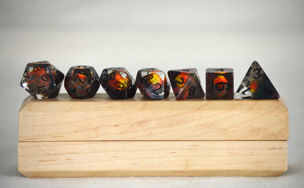 Dark resin Dungeons & Dragons dice set featuring glowing orange and yellow dragon egg cores; fantasy-themed polyhedral dice perfect for dragonborn and fire-aligned characters.