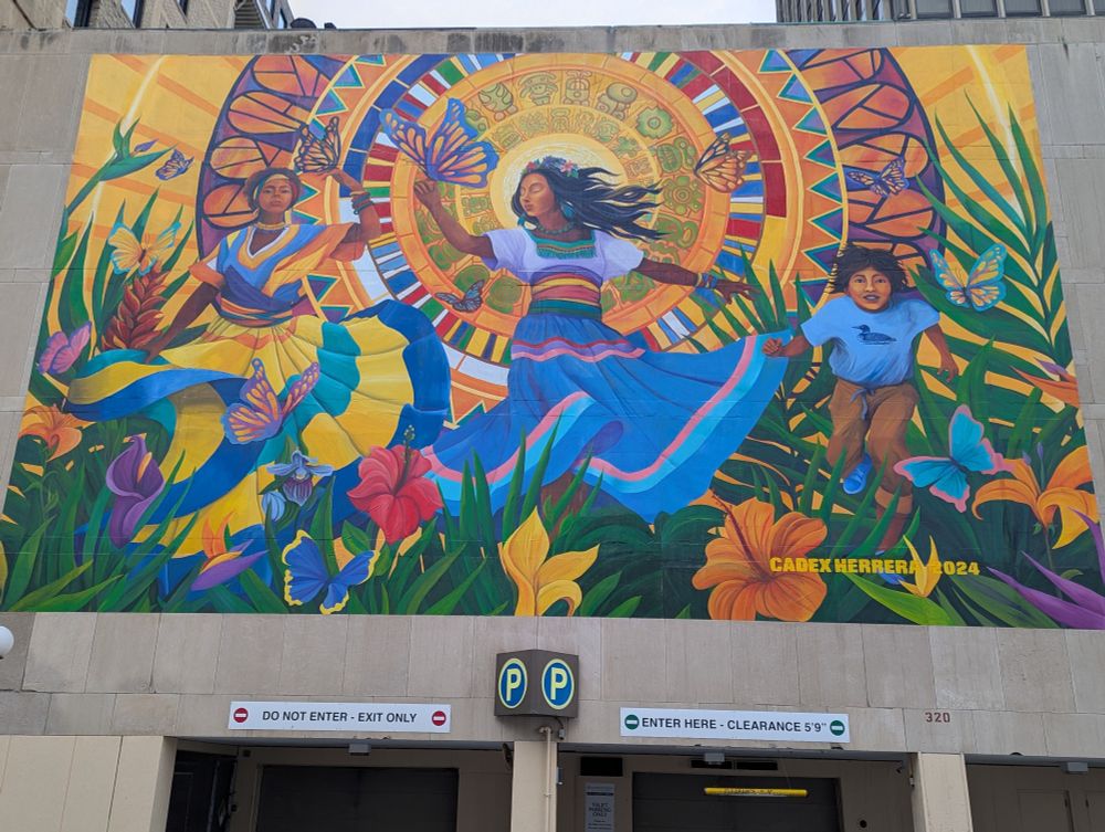A mural depicting brightly clad BIPOC folks dancing among flowers.

This mural is located at:
320 Wabasha St N, St Paul, MN 55102
