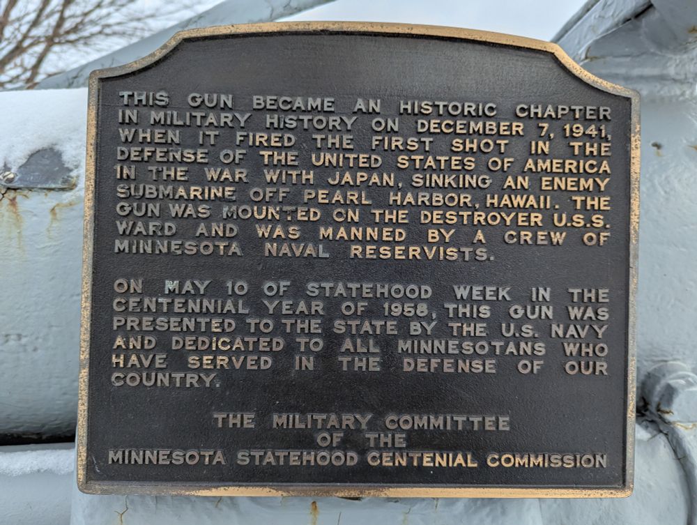 Brass plaque which reads:

This gun became an historic chapter in military history on December 7, 1941, when ti fired the firest shot in the defense of the United States of America in the war with Japan, sinking an enemy submarine off Pearl Harbor, hawaii.  The gun was mounted on the destroyer U.S.S. Ward and was manned by a crew of Minnesota Naval Reservists.

On May 10 of Statehood Week in the centennial year of 1958, this gun was presented to the state by the U.S. Navy and dedicated to all the Minnesotans who have served in the defense of our country.

The Military Committee of the Minnesota Statehood Centenial Commission