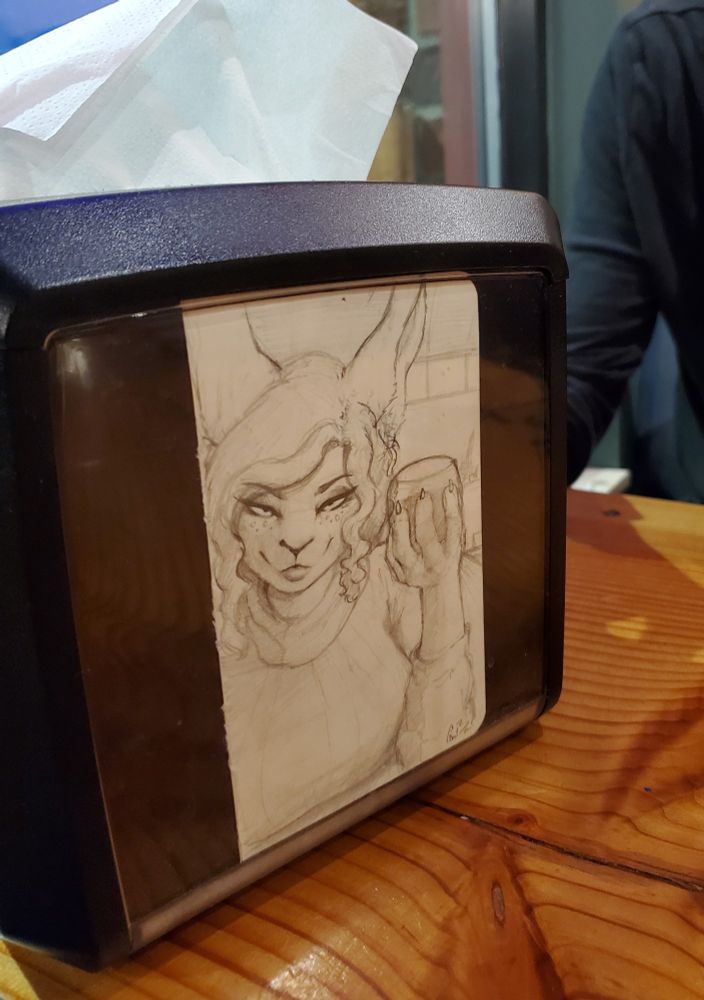 Picture of a napkin holder at Vulpine Taproom, with a sketch by Cinna of her holding a glass of wine