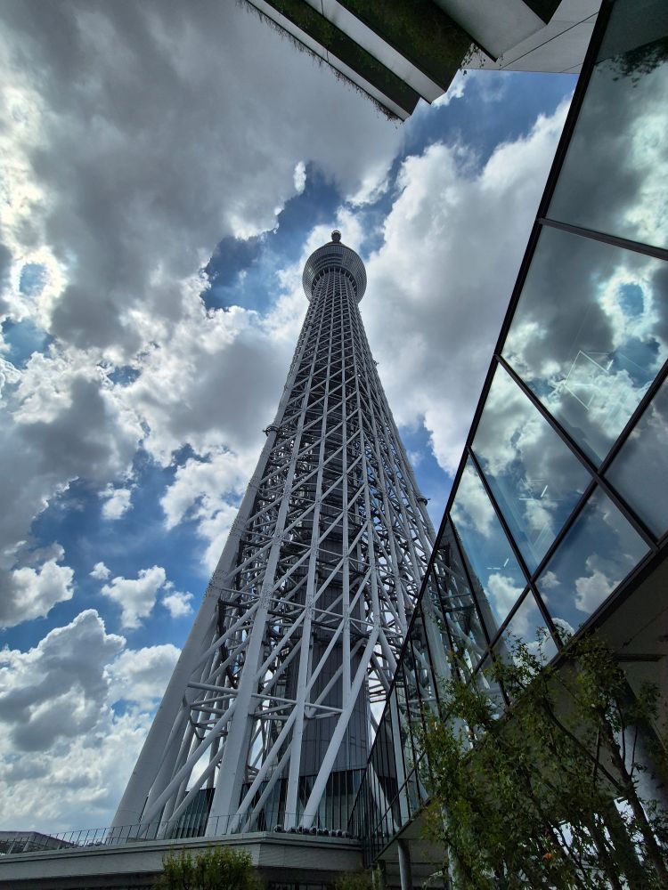 Une photo prise au pied de la Tokyo Skytree.
Elle est très imposante.
Le ciel est clairsemé. 