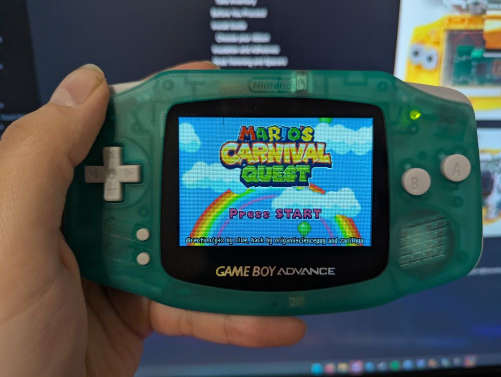 An original Gameboy Advance with a backlit screen, showing the romhack Mario's Carnival Quest by Planet Clue for Mario Party Advance 