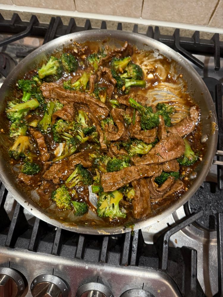 Broccoli beef in a stainless steel pan on the stove 