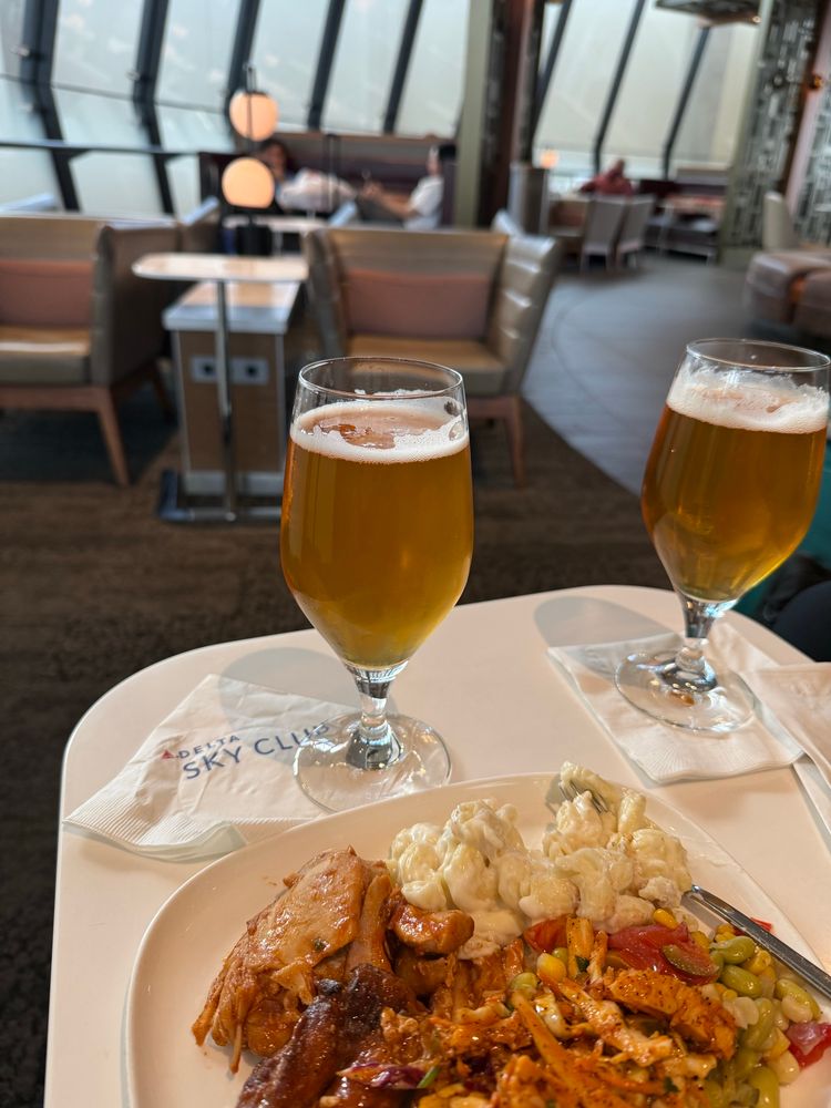 A beer and plate of chicken with Mac on a table at the delta sky club 