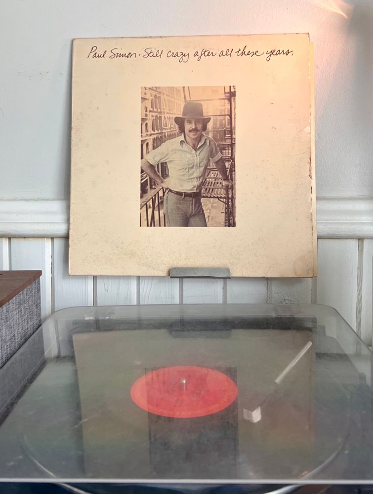 Turntable playing Paul Simon’s 1975 album Still Crazy After All These Years with the album cover showing the artist standing on a balcony.