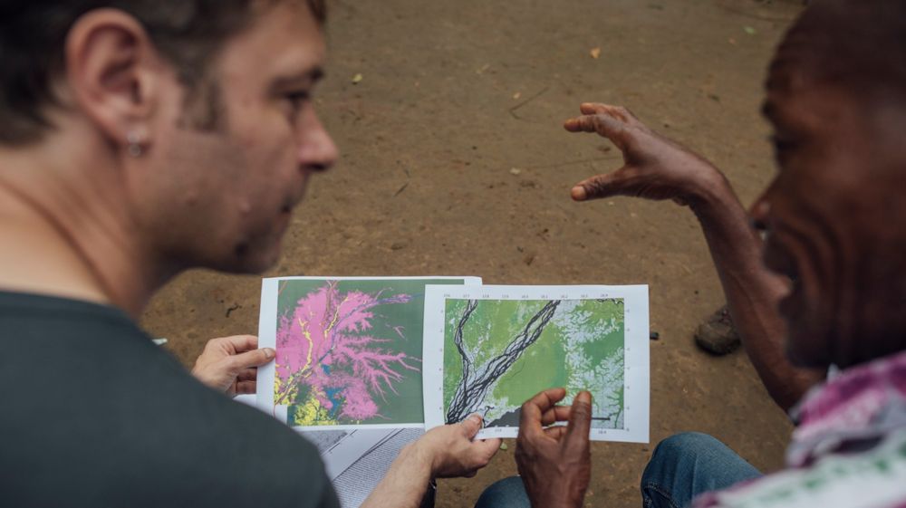 Two researchers from the CongoPeat research group are seen discussing maps of forest cover and peatland extent in the central Congo Peatlands
