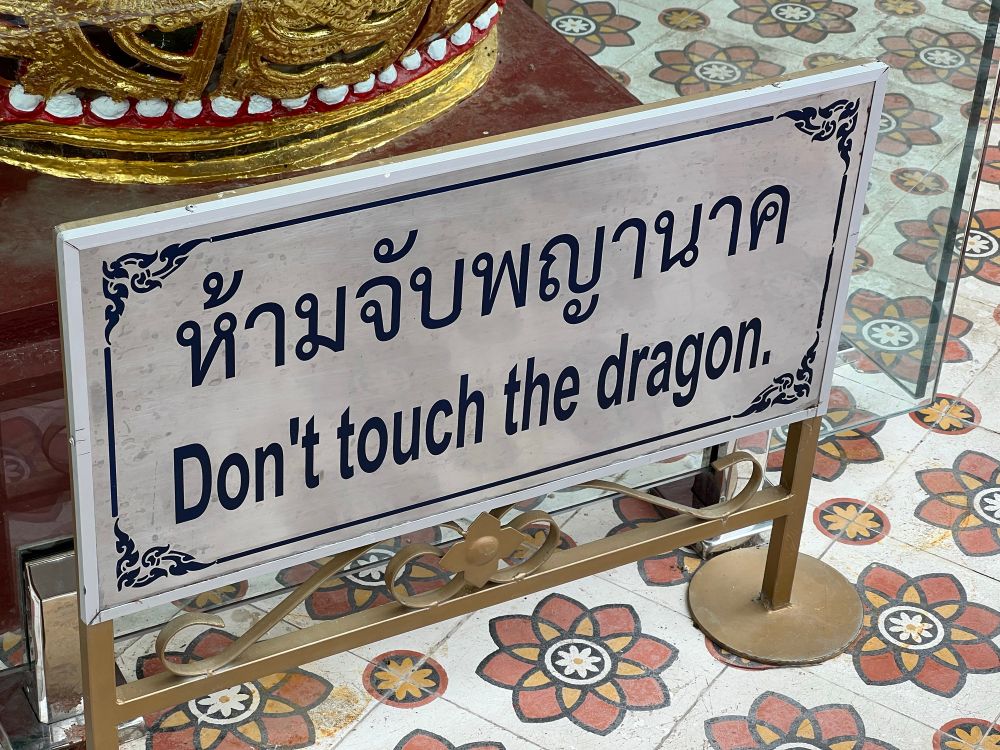 Sign in a Thai temple reading ‘Don’t touch the dragon’ in English and Thai. 