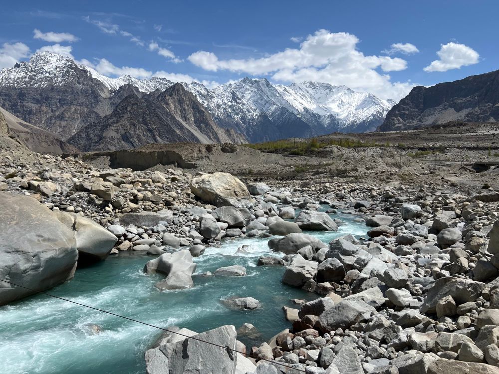 Aquamarine river in foreground with spectacular white capped mountains in distance