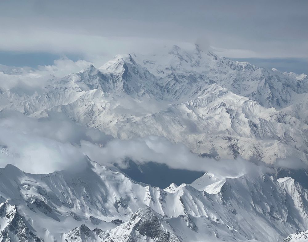 High altitude mountain range covered in snow and cloud