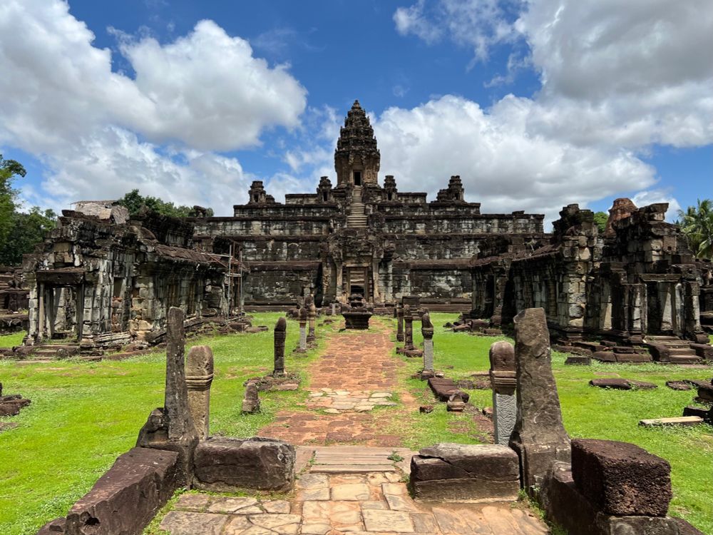 5 tiered pyramid temple with smaller ruined stone structures in front on either side 