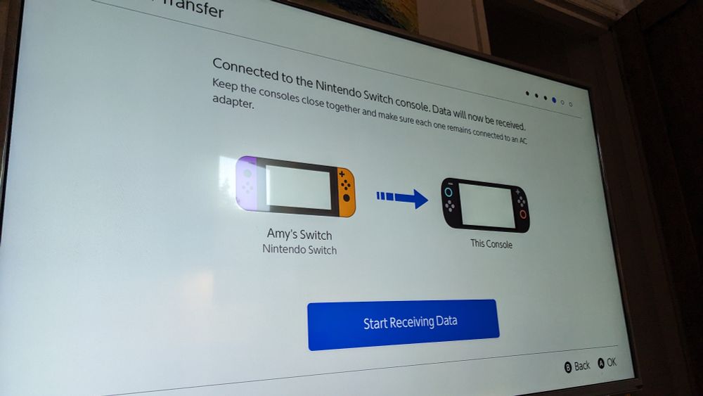 A photo of my TV. On the screen is a diagram showing a Switch with an arrow pointing to the Switch 2. A button on screen under the diagram says "Start Receiving Data"