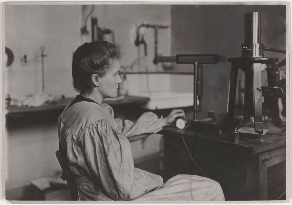 Marie Curie, chronomèter in hand, in the process of measuring radioactivity in the laboratory on Cuvier Street, 1904 © Association Curie Joliot-Curie.