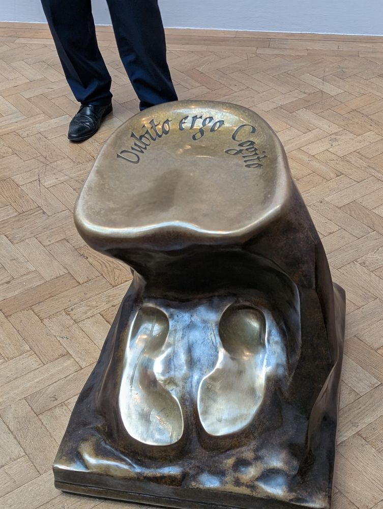 A bronze sculpture with a place to sit and foot places - all worn. Inscribed on the top is Sit and Think in Latin (I cannot remember what that is - sorry)