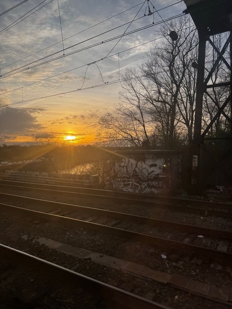 Sunset across train tracks, wall with graffiti and electric wires