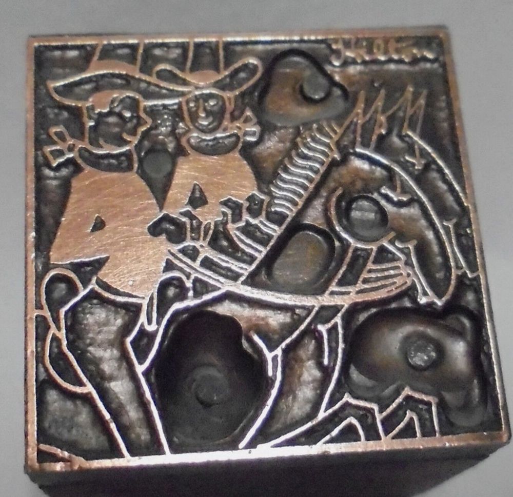 Historical letterpress block showing an image of two cowboys riding horses; one cowboy is smiling forward, and the other cowboy is smiling at the first cowboy