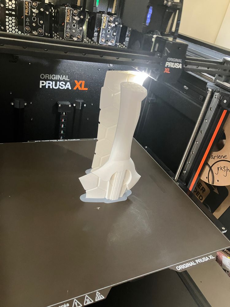 Photo of an in-progress 3D print in a 3D printer; the print looks like the handle of a fantasy sword in white filament