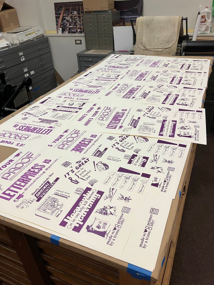 Photo of a large work table covered by copies of the letterpress print in the first photo, violet ink on cream paper
