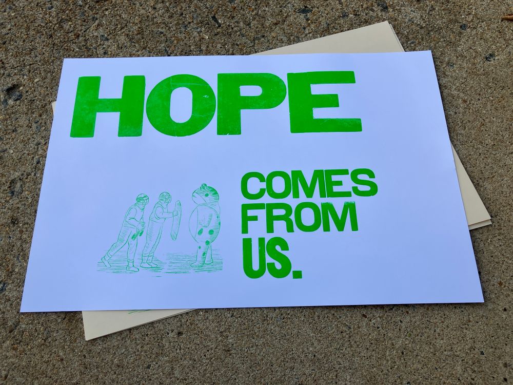 Photo of a letterpress print on white paper with bright green ink. It says "HOPE comes from us." over an image printed using a lasercut wood block made from @queermedieval.bsky.social's drawing of the Portland Frog standing up to evil government agents.