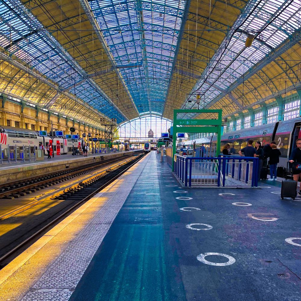 Un quai de la gare Bordeaux Saint Jean, avec un magnifique point de fuite coïncidant avec le TGV au bout dudit quai, magnifiques lumières bleutées et orangées avec le soleil fort peu haut dans le ciel 