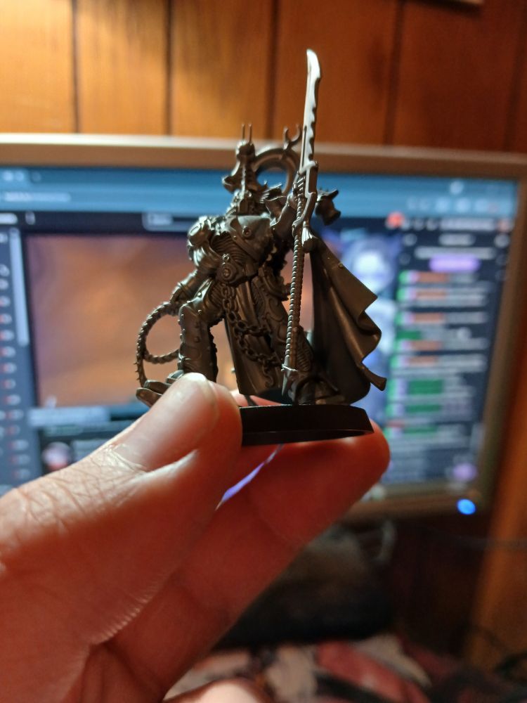 An unpainted Lord Exultant miniature for the tabletop wargame Warhammer 40k, held by the pale ass fingers of Malphas_Vtuber.