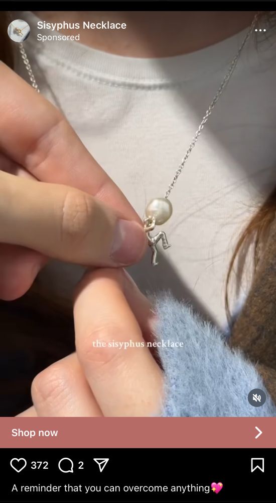 a picture of a necklace with a figure on it who is pushing some kind of pearl or bauble up the necklace chain, labeled “the Sisyphus necklace”… “a reminder that you can overcome anything” 