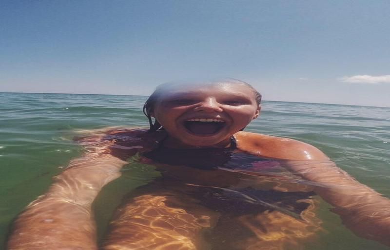 A girl smiles joyously while playing in the ocean.