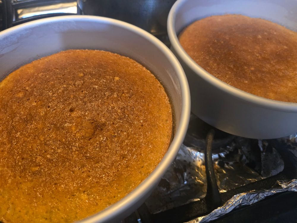 A pair of round banana cakes cooling in their pans