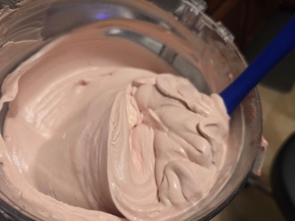 A mixing bowl full of light pink strawberry whipped cream