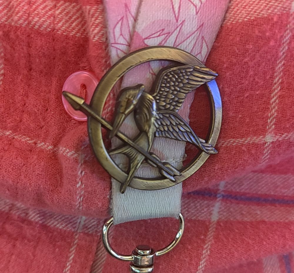 A Hunger Games mockingjay pin on a lanyard. 
