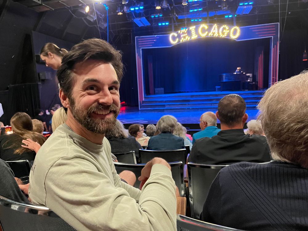 Me turning around in search of, smiling with stage and CHICAGO in lights in background 