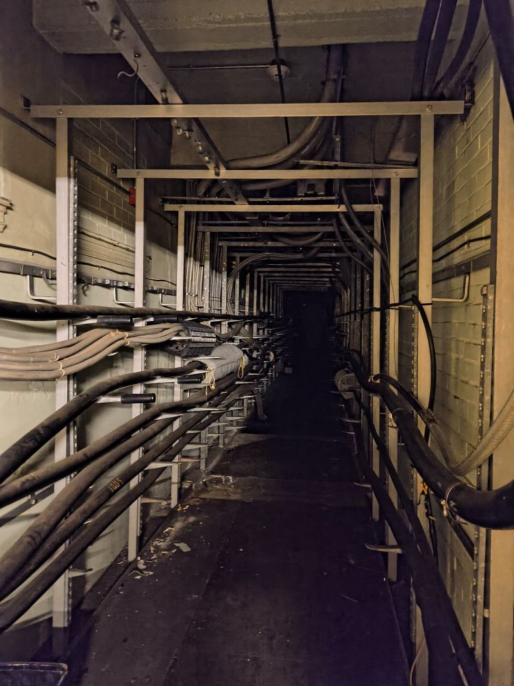 large, long dark hallway with several conduit tubes stretching into the dark