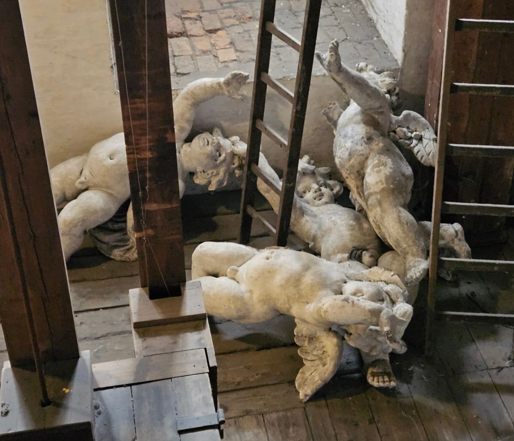 Four old statues of white angels lying on a wooden floor.