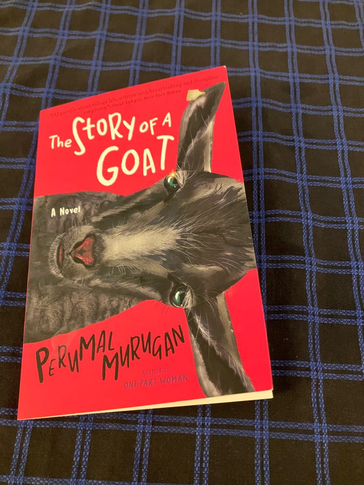 Picture of the book, story of a goat, by perumal murugan on a black tablecloth 