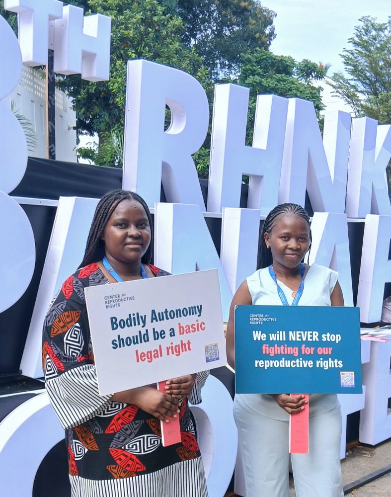 From left to right: Make Way youth representatives Elizabeth Warindi and Vilda Atieno standing and holding two signs. Warindi’s sign says: ‘Bodily autonomy should be a basic legal right’, and Vilda’s sign says: ‘We will never stop fighting for our reproductive rights.’