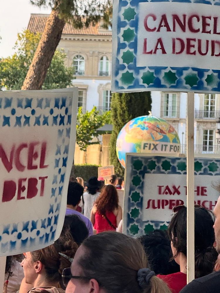 People with signs saying Tax the super rich and Cancel debt