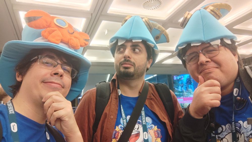 A selfie photo of Jorge, John and Moski doing the thinking face emoji during DevGAMM Lisbon 2025.