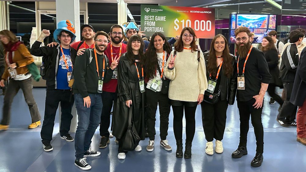A photo from DevGAMM taken immediately after the DevGAMM Awards, showing a big group of people celebrating the achievement and their time at the event. The group is composed of both us, other developers, and Portuguese content creators and media. I'm on the left of the picture doing a victory fist, while John holds the award check for Best Game from Portugal in the back.