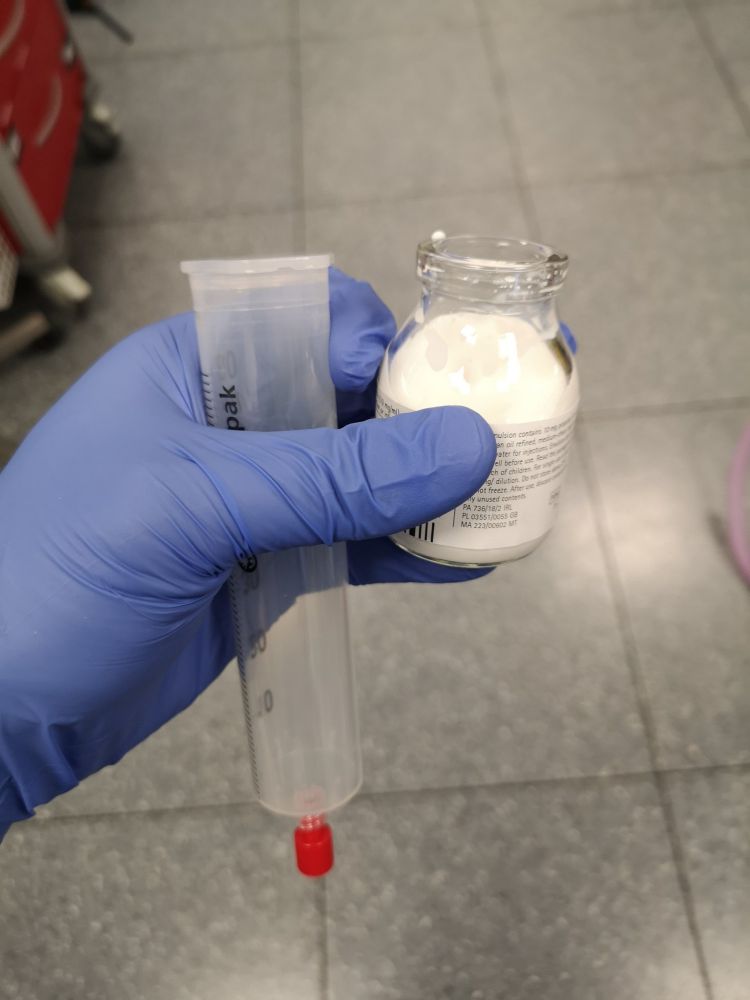 Drawing up propofol into a 50ml syringe by pouring into an open syringe with the plunger removed.