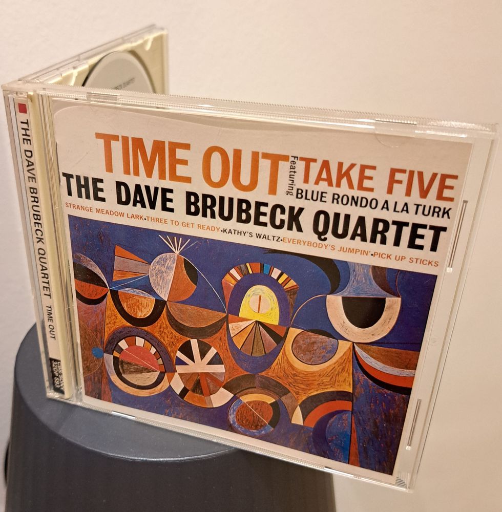 A CD album of The Dave Brubeck Quartet's Time Out, open ajar so that the front and side of the jewel case is visible.

The catalog number (on black at the bottom of the side label) reads "CBS/SONY, 32DP 593".