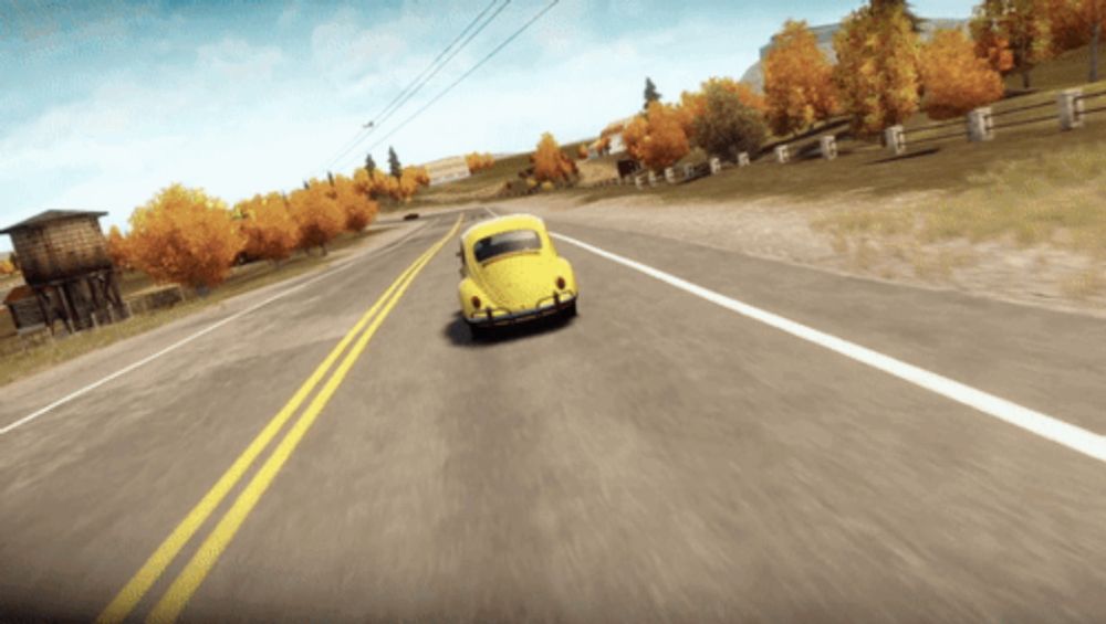 a yellow car is driving down a road with a fence in the background