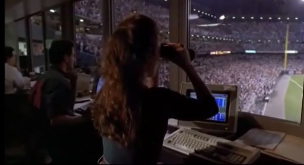 Stadium operator in press box sees Rick Vaughn entering in his leather jacket in MAJOR LEAGUE 2
