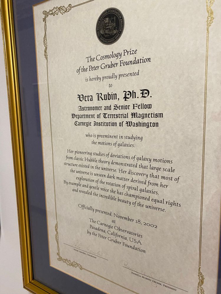Framed copy of 2002 Gruber Cosmology Prize awarded to Vera Rubin, which reads, “Her pioneering studies of the deviations of galaxy motions from classical a Hubble theory demonstrated that large scale structure existed in the universe. Her discovery that most of the universe is unseen dark matter derived from her exploration of the rotation of spiral galaxies. By example and gentle voice she has championed equal rights and revealed the incredible beauty of the universe.” 