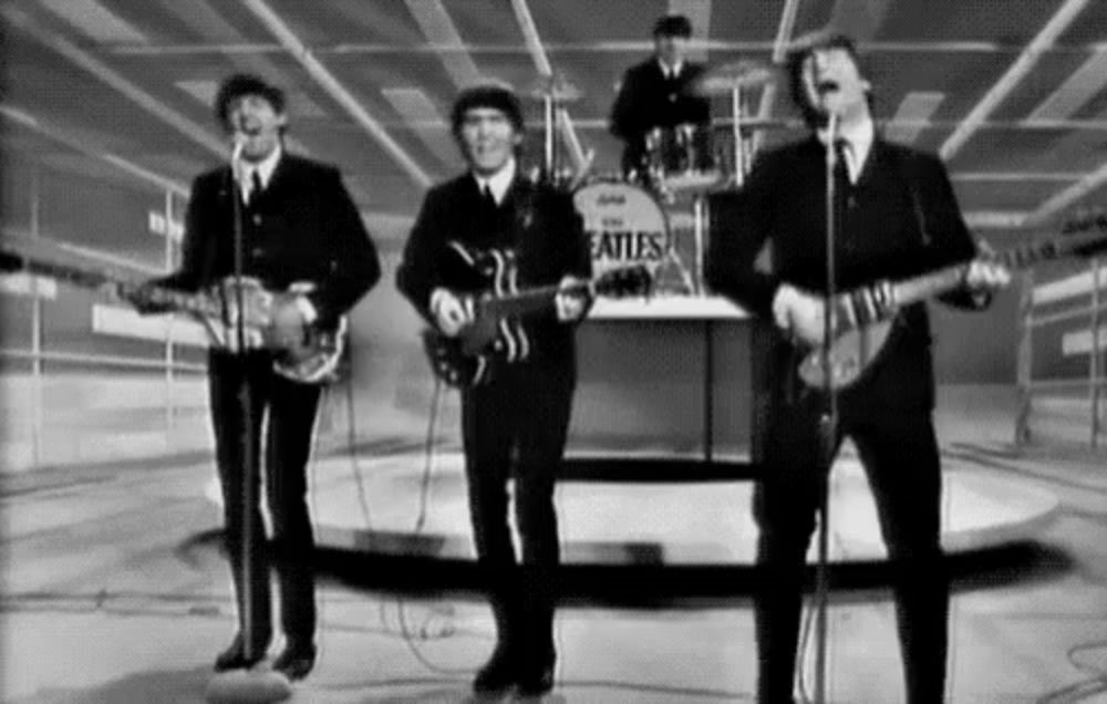 a black and white photo of the beatles performing on stage .