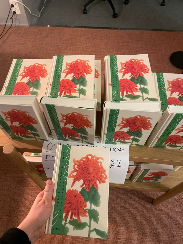 Monta Aura Nurmen Karkuteillä-romaania. Kirjan kannessa on punaisia kukkia.