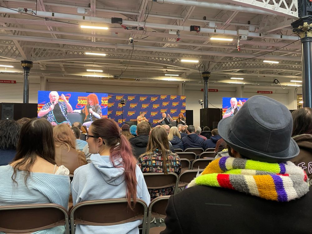Colin Baker and Bonnie Langford speaking on the main stage in front of rows of dedicated Doctor Who fans.