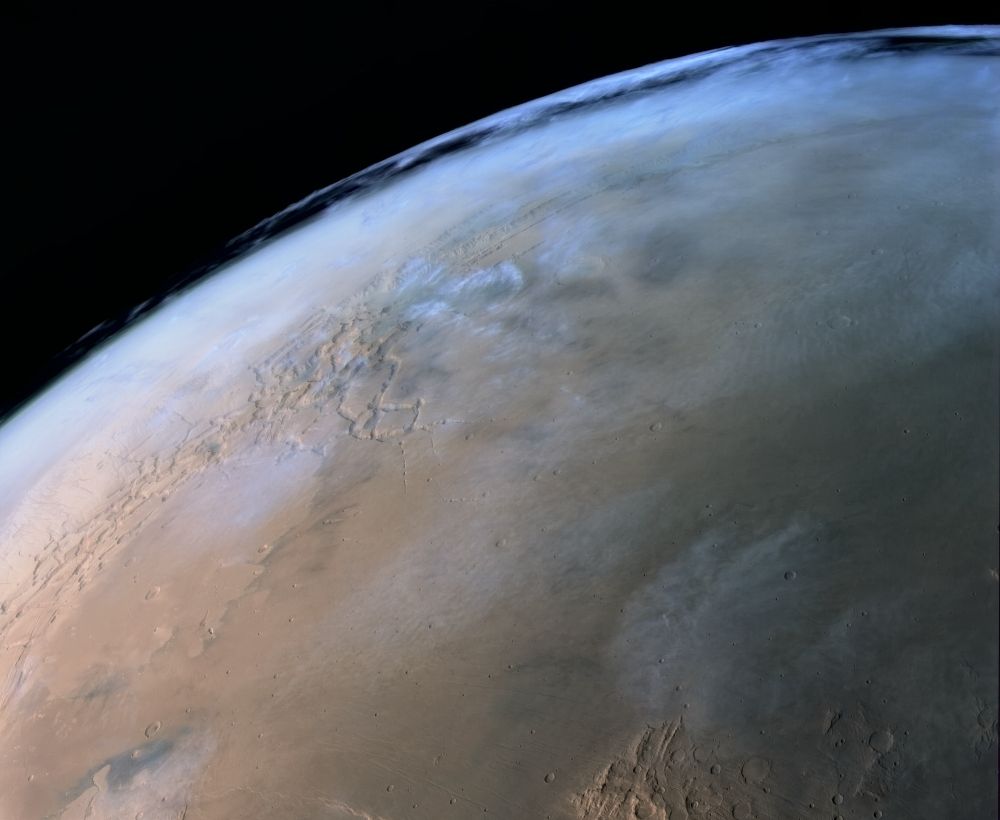 Color image of high altitude clouds over Martian canyon Valles Marineris. 
Valles Marineris is visible at the top right of the image under another layer of lower altitude clouds.
Clouds at lower altitudes are also visible across different parts of the image with other prominent Martian features such as Noctis Labyrinthus and Syria Planum to the left and Sinai and Solis Planum in the right part of the image.