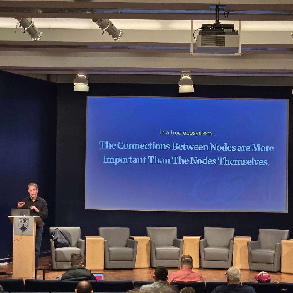 Ben Pate presenting at Fedicon with a slide that says "in a true ecosystem the connections between nodes are more important than the nodes themselves"