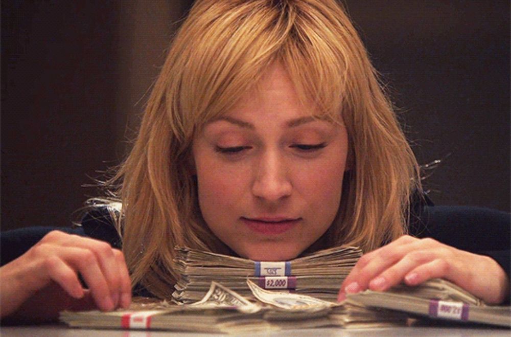 Parker from Leverage staring at and stroking a pile of cash